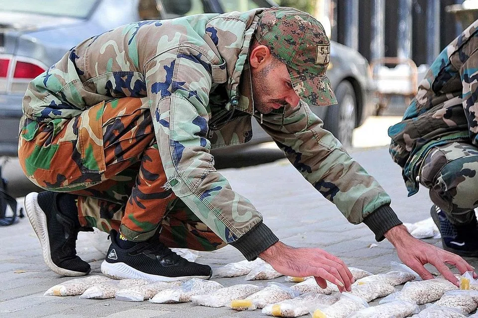 RAMPASAN DADAH 'CAPTAGON': Gambar yang dirakamkan Agensi Berita Arab Syria (SANA) pada 30 November lalu menunjukkan kakitangan pasukan keselamatan menyusun beg mengandungi bahan perangsang 'captagon' yang telah dirampas pihak berkuasa. Ia tersembunyi dalam 525 kilogram pasta dalam satu bekalan menuju Arab Saudi. - Foto AFP 