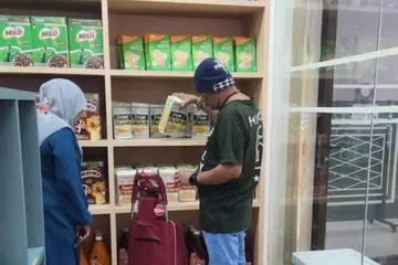 Sukarelawan Eksekutif Muslimah di Masjid Hasanah (kiri) membantu penerima manfaat di Komuniti Pantri@Hasanah. 