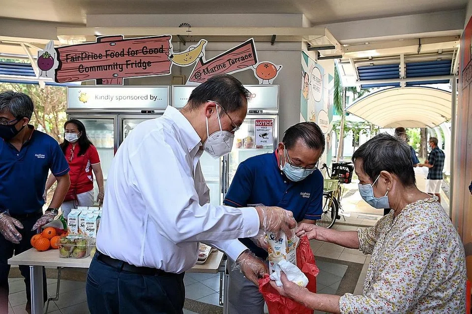 BERKONGSI MAKANAN: Dr Tan (berkemeja putih), dengan Encik Seah (dua dari kanan) membantu mengagihkan makanan untuk mereka yang memerlukan di kolong Blok 20, Marine Terrace, semalam. - Foto BH oleh KUA CHEE SIONG