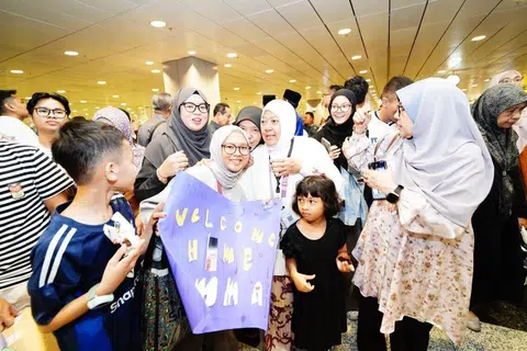 Cik Aqilah Jumaat (barisan belakang, dua dari kiri) hadir menyambut kepulangan ibunya, Cik Zaidah Ahmad (barisan kedua, dua dari kanan).