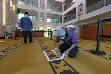 PERSIAPAN BERJALAN LANCAR: Kakitangan Masjid Mujahidin sedang menyiapkan ruang solat mengikut garis panduan yang diberikan oleh Muis menjelang pembukaan semula masjid-masjid di Singapura Selasa depan. Kotak putih yang dilekatkan di permaidani dalam zon individu menandakan tempat jemaah individu berdiri, pada jarak dua meter dari jemaah lain. Kawasan yang dikepung dengan papan pula diperuntuk bagi zon isi keluarga. Sehingga lima individu dibenarkan berada satu zon solat pada satu masa. - Foto BH oleh GAVIN FOO