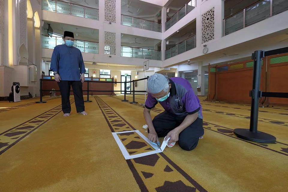 PERSIAPAN BERJALAN LANCAR: Kakitangan Masjid Mujahidin sedang menyiapkan ruang solat mengikut garis panduan yang diberikan oleh Muis menjelang pembukaan semula masjid-masjid di Singapura Selasa depan. Kotak putih yang dilekatkan di permaidani dalam zon individu menandakan tempat jemaah individu berdiri, pada jarak dua meter dari jemaah lain. Kawasan yang dikepung dengan papan pula diperuntuk bagi zon isi keluarga. Sehingga lima individu dibenarkan berada satu zon solat pada satu masa. - Foto BH oleh GAVIN FOO
