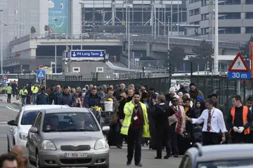 TINGGALKAN TEMPAT KEJADIAN: Orang ramai meninggalkan tempat kejadian letupan di Lapangan Terbang Zaventem, dekat Brussels, Belgium, semalam. - Foto REUTERS 