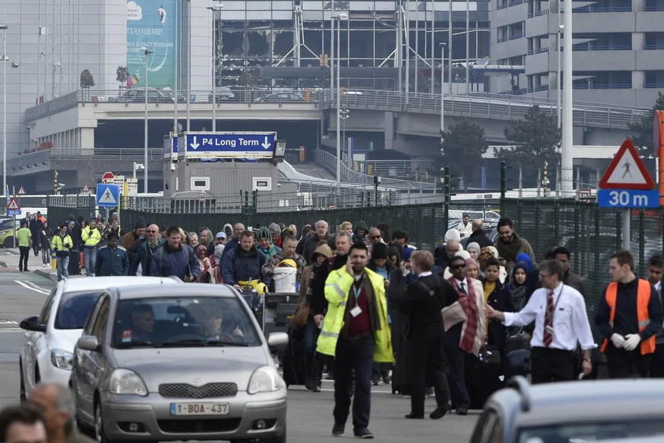 TINGGALKAN TEMPAT KEJADIAN: Orang ramai meninggalkan tempat kejadian letupan di Lapangan Terbang Zaventem, dekat Brussels, Belgium, semalam. - Foto REUTERS 