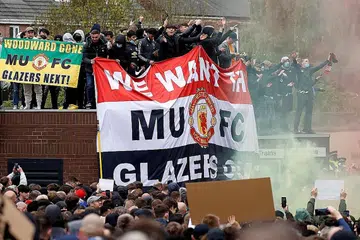 LAKUKAN BANTAHAN: (Gambar atas) Penyokong melakukan protes terhadap pemilik Manchester United di luar dan dalam Stadium Old Trafford dekat Manchester. - Foto REUTERS