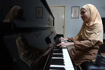 MAIN PIANO DENGAN MENDENGAR: Cik Siti Sakinah Zainal bermain piano dengan mendengar dan menghafal irama tersebut. Beliau anggota Purple Symphony, orkestra inklusif terbesar Singapura. - Foto BH oleh NG SOR LUAN