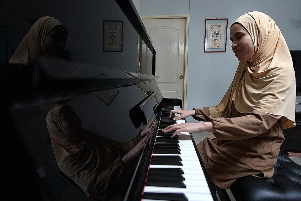 MAIN PIANO DENGAN MENDENGAR: Cik Siti Sakinah Zainal bermain piano dengan mendengar dan menghafal irama tersebut. Beliau anggota Purple Symphony, orkestra inklusif terbesar Singapura. - Foto BH oleh NG SOR LUAN