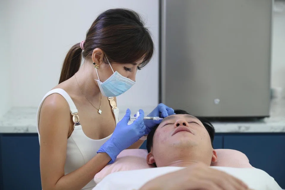 RAWATAN MUKA: Dr Samantha Tay (kiri) melakukan rawatan muka ke atas seorang pesakit lelaki. Beliau berkata bilangan kaum Adam yang datang untuk mendapatkan rawatan muka telah meningkat sejak beberapa tahun lalu. 