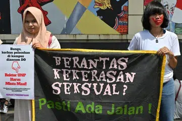Aktivis hak wanita memegang sepanduk bertulis “Hapuskan keganasan seksual? Pasti ada caranya!” pada 10 Februari 2020 semasa protes menentang gangguan dan keganasan seksual terhadap wanita di kampus, di luar Kementerian Pendidikan dan Kebudayaan di Jakarta.