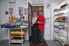 SEDIA MEMBANTU: Cik Norhasyimah Awaludin dan suami Encik Asanul Fariq Sani di  luar pintu rumah mereka yang menyediakan pelbagai barangan runcit untuk kegunaan sesiapa saja yang memerlukan.