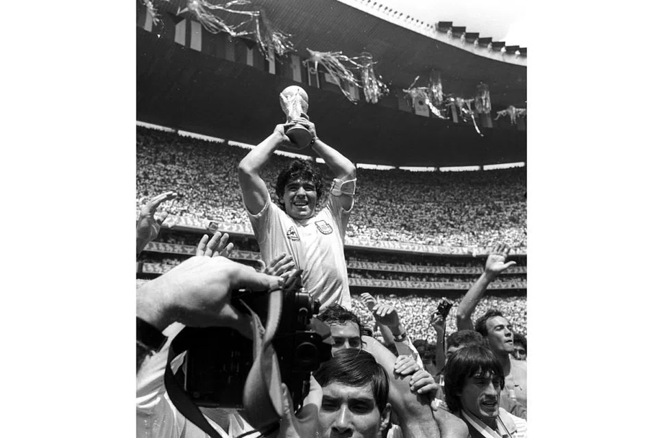 SAAT KEGEMILANGAN: Maradona menjunjung trofi Piala Dunia dan dijunjung rakan dan peminat selepas Argentina mengalahkan Jerman Barat 3-2 dalam Piala Dunia di Mexico pada 1986. - Foto REUTERS 