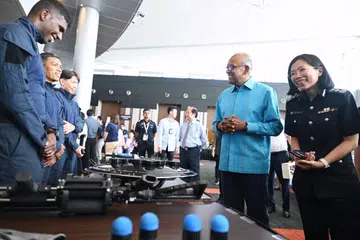 Menteri Ehwal Dalam Negeri merangkap Undang-Undang, Encik K Shanmugam (dua dari kanan), dan Pesuruhjaya Penjara, Cik Shie Yong Lee (kanan), berinteraksi dengan pegawai Perkhidmatan Penjara Singapura (SPS) semasa acara Kemajuan Korporat SPS dan Reben Kuning Singapura di Singapore Expo pada 30 April.