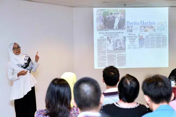KONGSI PENGALAMAN: Wartawan BH, Cik Shahida Sarhid (kiri), menjelaskan kepada peserta tentang kategori berita yang berbeza sempena Jejak Pembelajaran guru di Singapore Press Holdings semalam. - Foto M.O. SALLEH