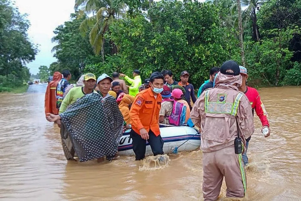 BANTU PENDUDUK: Sekumpulan pasukan penyelamat sedang memindahkan penduduk yang terjejas oleh banjir di Tanah Laut, Kalimantan Selatan, menggunakan bot getah. - Foto AFP