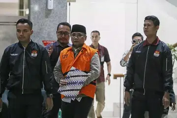 Bekas Menteri Hal Ehwal Agama Indonesia, Yaqut Cholil Qoumas (tengah), diiring oleh pegawai Suruhanjaya Pemberantasan Rasuah (KPK) selepas disoal siasat di bangunan suruhanjaya itu di Jakarta pada Khamis, 12 Mac 2026.