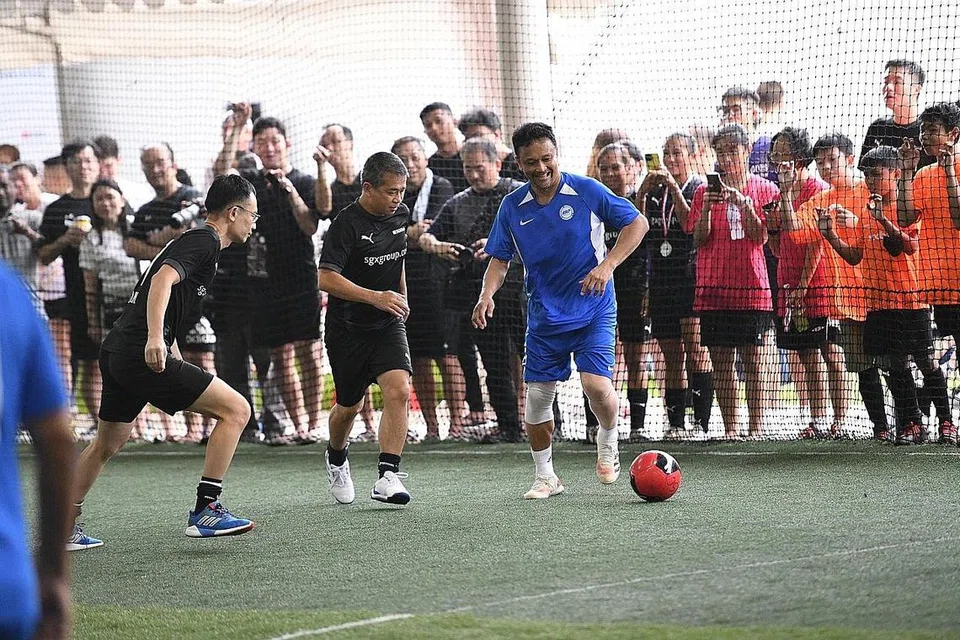 TUNJUK KEBOLEHAN: Encik Edwin Tong (tengah) dan Fandi Ahmad (kanan) beraksi untuk mengumpul $111,000 dalam acara Futsal Amal Singapore Exchange Bull Charge. - Foto SGX