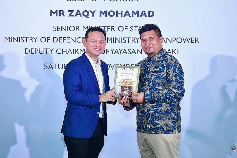 SUMBANGAN TUTOR DIIKTIRAF: Menteri Negara Kanan (Pertahanan merangkap Tenaga Manusia), Encik Zaqy Mohamad menyampaikan Anugerah Sumbangan Terbaik kepada salah seorang penerima, pendidik dan tutor MTS sepanjang sembilan tahun, Encik Muhammad Jailani Abu Talib ketika acara penyampaian Anugerah Tutor Mendaki di HomeTeamNS Khatib. - Foto MENDAKI