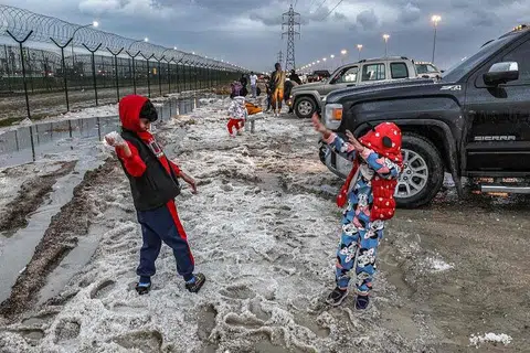 BERMAIN DENGAN AIS BATU: Kanak-kanak memakai baju hujan sedang mereka bermain dengan ais batu di daerah Umm al-Haiman, kira-kira 50 kilometer ke selatan Kuwait City. 