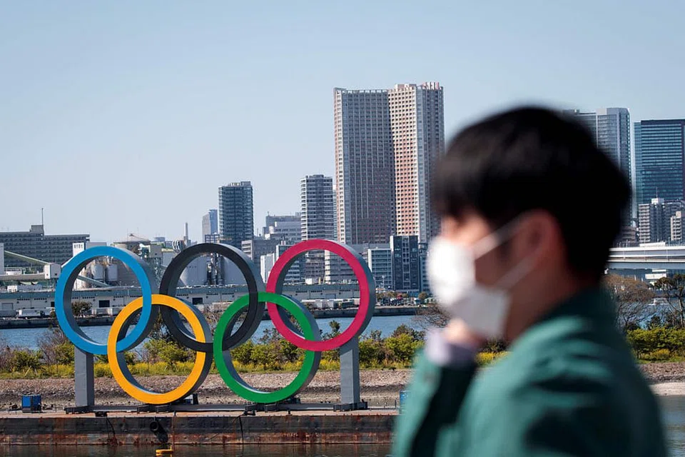 TUNGGU TAHUN DEPAN: Seorang lelaki memakai pelitup berdiri dekat gelang Olimpik di kawasan Odaiba, Tokyo. - Foto AFP