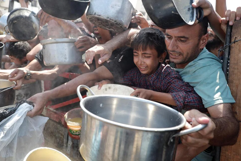 Warga Palestin berebut-rebut mendapatkan makanan yang diagihkan oleh sebuah badan amal di tengah-tengah krisis makanan yang kini melanda Gaza