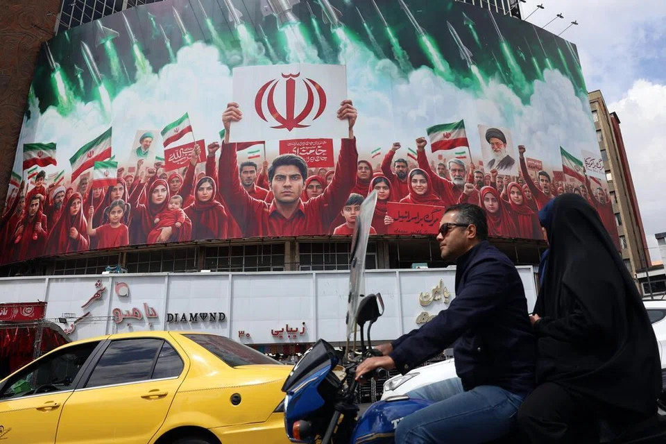 Penduduk Iran melepasi papan iklan politik besar yang memaparkan bendera kebangsaan Iran di Dataran Valiasr, Tehran pada 6 April 2026 ketika Iran mengemukakan cadangan yang menggariskan pendiriannya untuk menamatkan peperangan, dengan menolak gencatan senjata sementara dan sebaliknya menuntut penyelesaian yang kekal.