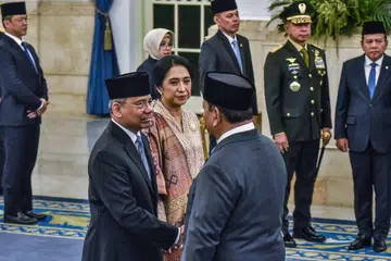 Presiden Indonesia, Encik Prabowo Subianto (kanan), bersalaman dengan Menteri Kewangan yang baru dilantik, Encik Suahasil Nazara (kiri), sambil diperhatikan isterinya, Cik Christina Pusporini Messakh, dalam upacara mengangkat sumpah di Istana Presiden di Jakarta pada 14 September 2026. Encik Suahasil, yang sebelum ini Timbalan Menteri Kewangan, dilantik menggantikan Encik Purbaya Yudhi Sadewa dalam rombakan Kabinet secara mengejut.