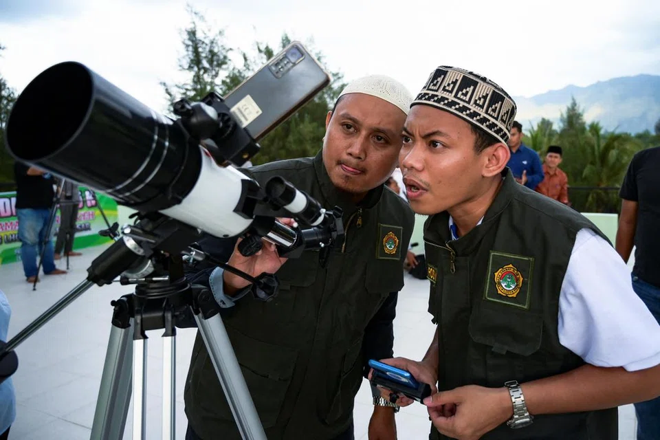 Dua pegawai melihat kedudukan anak bulan untuk menandakan hari pertama Ramadan di sebuah balai cerap di Lhoknga, Aceh, Indonesia, pada 10 Mac.