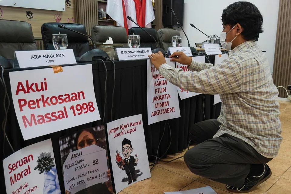 Seorang aktivis menampal beberapa poster, termasuk yang bertulis “akui rogol beramai-ramai 1998”, menjelang sidang media di pejabat Suruhanjaya Kebangsaan Mengenai Keganasan terhadap Wanita (Komnas Perempuan) di Jakarta pada 22 April 2026. 