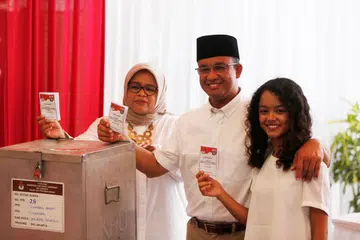 PETANDA AWAL: Calon gabenor, Encik Anies Baswedan, membuang undi bersama-sama isterinya, Cik Fery Farhati Ganis (kiri) dan anak perempuan mereka, Mutiara Annisa, bagi pemilihan jawatan Gabenor Jakarta, di Jakarta Selatan, pagi tadi. - Foto REUTERS