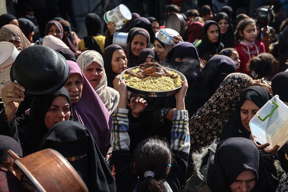 Warga Palestin yang dipindahkan berkumpul untuk menerima agihan makanan di sebuah dapur amal di kem pelarian Nuseirat, tengah Jaluran  Gaza, pada 20 Disember 2025. Kebuluran yang diisytiharkan di Gaza pada Ogos lalu kini telah berakhir susulan peningkatan akses bantuan kemanusiaan, menurut Pertubuhan Bangsa-Bangsa Bersatu pada 19 Disember 2025. Namun, PBB memberi amaran bahawa situasi makanan di wilayah Palestin itu masih kritikal. Walaupun gencatan senjata antara Israel dan kumpulan militan Hamas yang berkuat kuasa sejak Oktober telah melonggarkan sebahagian sekatan terhadap barangan dan bantuan, penghantaran bantuan kekal tidak menentu, terhad dan tidak sekata di seluruh Gaza. (Foto oleh Eyad Baba / AFP)