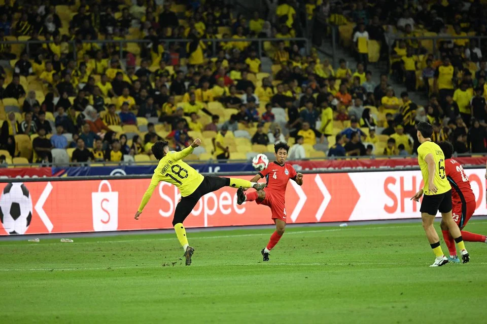 Pemain sayap Singapura, Nazrul Nazari, bertarung dengan pemain Malaysia untuk merebut bola. Walaupun Singapura menghasilkan persembahan yang hambar, mereka berjaya mendapatkan keputusan seri yang mereka perlukan untuk ke peringkat separuh akhir Piala AFF. 