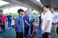 Perdana Menteri, Encik Lawrence Wong (berkemeja putih), bertemu dengan penduduk Punggol, Cik Nur Izyani Taha (bertudung), yang hadir di majlis pelancaran One Punggol bersama suaminya, Encik Suhaidi Dali (dua dari kiri), anak lelakinya, Hadi Irfan, dan anak perempuannya, Hanis Arianna.