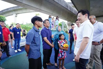 Perdana Menteri, Encik Lawrence Wong (berkemeja putih), bertemu dengan penduduk Punggol, Cik Nur Izyani Taha (bertudung), yang hadir di majlis pelancaran One Punggol bersama suaminya, Encik Suhaidi Dali (dua dari kiri), anak lelakinya, Hadi Irfan, dan anak perempuannya, Hanis Arianna.