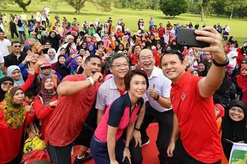 BERAMAI-RAMAI MENUJU GAYA HIDUP SIHAT: Encik Zaqy (memegang telefon bimbit), Cik Low (berbaju merah jambu), Encik Gan (berbaju putih, di belakang Cik Low) dan Encik Yee (berbaju putih) mengambil swafoto bersama dengan sebahagian daripada sekitar 600 peserta dalam acara Perjalanan Hijrah 2018 semalam. - Foto FACEBOOK ZAQY MOHAMAD