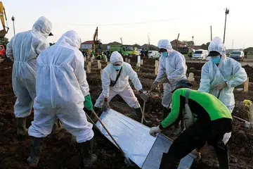 KEMATIAN TERUS MENINGKAT: Pekerja yang siap memakai alat pelindungan diri (PPE) mengebumikan pesakit yang maut akibat jangkitan Covid-19 di sebuah tanah perkuburan yang disediakan bagi korban virus itu di Jakarta kelmarin. Jumlah kes dan kematian baru Covid-19 di Indonesia terus meningkat, dengan 891 orang maut kelmarin. - Foto REUTERS