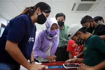 PENDIGITALAN BAGI SEMUA: Cik Rahayu Mahzam (dua dari kiri) bersama Anggota Parlimen bagi GRC West Coast, Encik Ang Wei Neng (tiga dari kiri, baju hijau), menyaksikan seorang individu melakukan aktiviti dalam talian di bengkel celik digital di Kelab Masyarakat Nanyang pada Februari tahun ini.