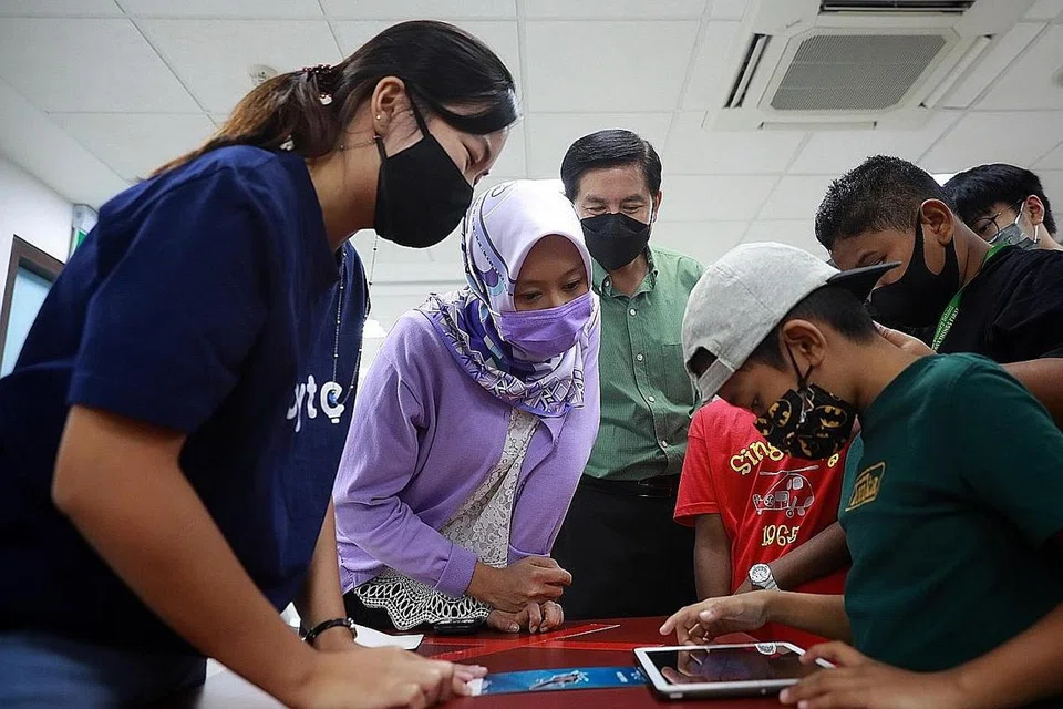 PENDIGITALAN BAGI SEMUA: Cik Rahayu Mahzam (dua dari kiri) bersama Anggota Parlimen bagi GRC West Coast, Encik Ang Wei Neng (tiga dari kiri, baju hijau), menyaksikan seorang individu melakukan aktiviti dalam talian di bengkel celik digital di Kelab Masyarakat Nanyang pada Februari tahun ini.