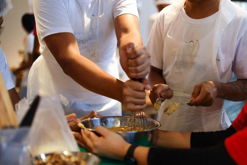 BIMBING SAMBIL LAKUKAN AMAL: Para sukarelawan NUS #PARADIGMA dan belia berisiko membantu membersihkan rumah penerima bantuan sebagai sebahagian aktiviti yang dijalankan. Foto NUS #PARADIGMA