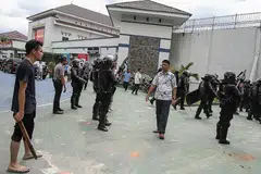 AWASI KEADAAN: Seorang penduduk yang tinggal berdekatan penjara Sialang Bungkuk dan pegawai keselamatan berjaga-jaga selepas kira-kira 200 banduan meloloskan diri, - Foto REUTERS