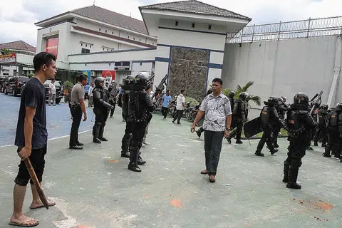 AWASI KEADAAN: Seorang penduduk yang tinggal berdekatan penjara Sialang Bungkuk dan pegawai keselamatan berjaga-jaga selepas kira-kira 200 banduan meloloskan diri, - Foto REUTERS