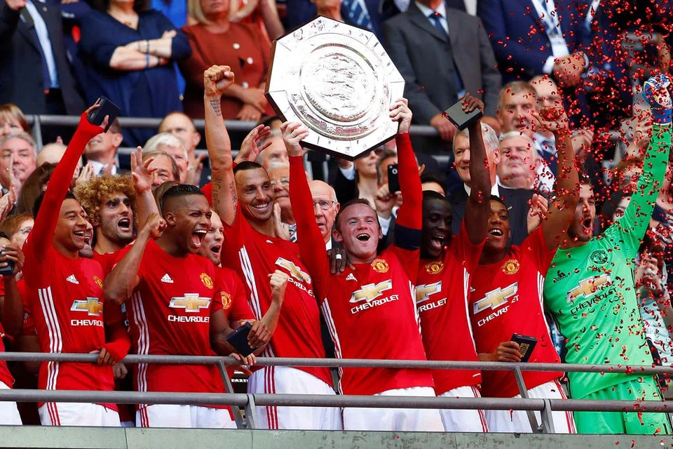 TROFI PERTAMA MUSIM: Kapten United, Wayne Rooney, menjulang Perisai Masyarakat selepas kejayaan 2-1 ke atas Leicester di Wembley kelmarin. Di kanannya ialah bintang baru pasukan yang menyumbatkan gol kemenangan United, Zlatan Ibrahimovic. - Foto REUTERS