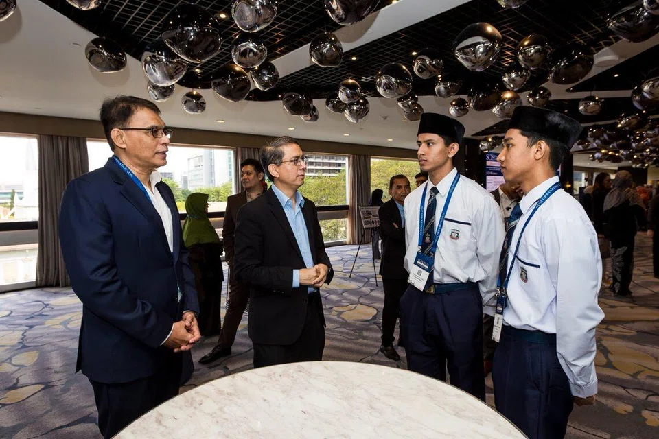 Dr Faishal (dua dari kiri) menekankan peranan asatizah menjangkaui sekadar pengajaran ilmu agama. Mereka menyokong masyarakat dalam menangani cabaran kehidupan sebenar, termasuk isu perkahwinan, pendidikan, keluarga, dan pekerjaan. Bersama beliau dalam foto ialah Ketua Eksekutif Muis, Encik Kadir Maideen (kiri) dan pelajar madrasah yang menyertai Simposium SCIS pada 27 Januari.