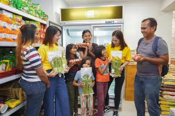 SEGAR, SEIMBANG: Sukarelawan RWS (berbaju kuning) menemani keluarga seorang penerima, Cik Siti Rosninah Mohamed Husin (kiri), untuk memilih makanan yang segar dan sihat di Kedai Komuniti di Boon Lay.