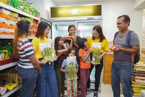 SEGAR, SEIMBANG: Sukarelawan RWS (berbaju kuning) menemani keluarga seorang penerima, Cik Siti Rosninah Mohamed Husin (kiri), untuk memilih makanan yang segar dan sihat di Kedai Komuniti di Boon Lay.