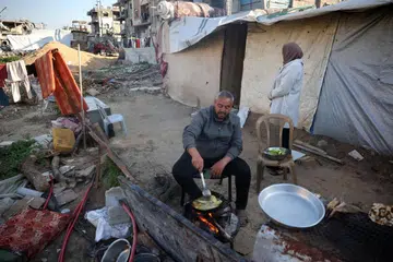 Seorang lelaki Palestin sedang memasak juadah berbuka puasa di luar tempat perlindungannya di kem pelarian Bureij, yang terletak di tengah Semenanjung Gaza, pada 11 Mac 2025 sempena bulan suci Ramadan.