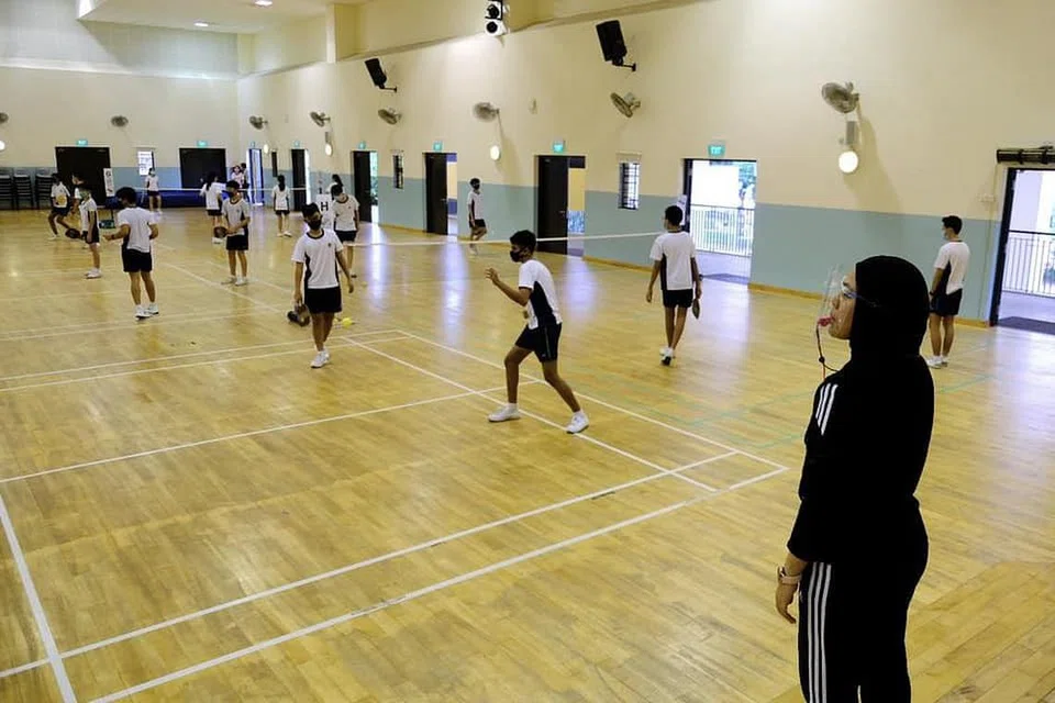 Pelajar Menengah 2 di Sekolah Menengah Ngee Ann bermain 'pickleball' sambil mematuhi langkah pengurusan selamat.