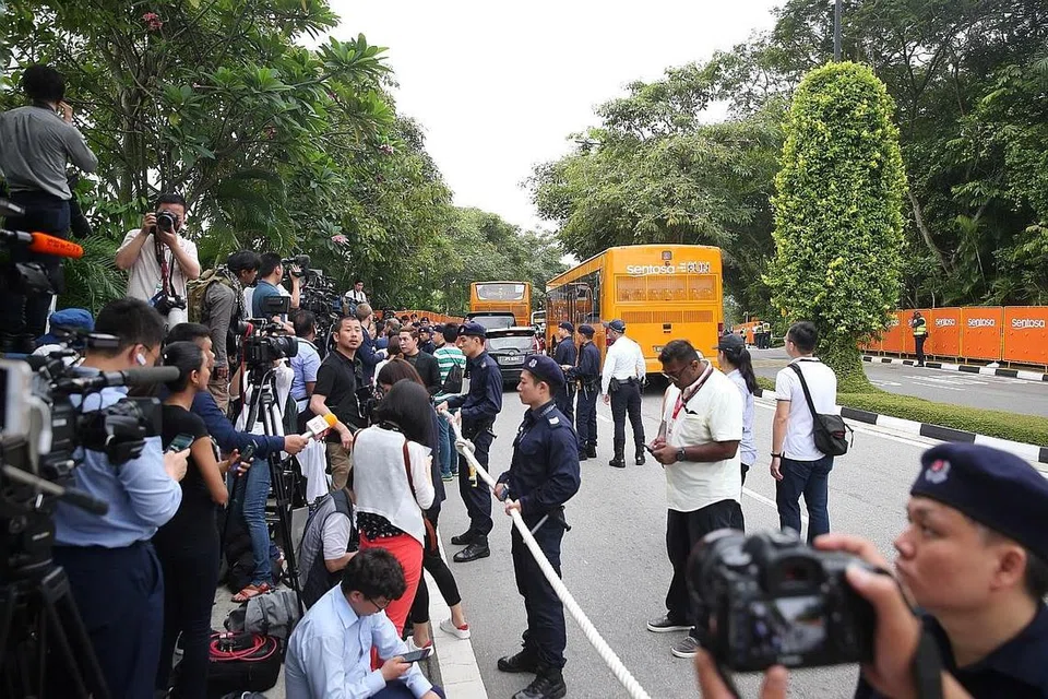 MENINJAU PERKEMBANGAN: Dengan memanjangkan leher sambil bersedia dengan video dan kamera di tangan, orang ramai, pelancong dan wartawan bergesel bahu untuk mengikuti perkembangan sidang puncak di Sentosa, dengan dikawal pasukan keselamatan. - Foto BM oleh GAVIN FOO 
