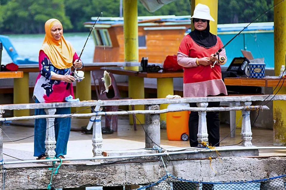 WAH! SERONOK MEMANCING: Pengunjung seronok dapat memancing di kelong tempat mereka menginap. 