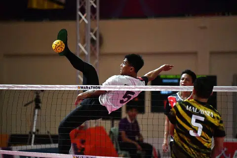RAIH PENGALAMAN: Pemain Singapura Khairul Fahmi Yazid membuat serangan libas ketika menentang Malaysia dalam acara regu lelaki di Sukan SEA 2023 pada Selasa. - Foto MAJLIS KEBANGSAAN OLIMPIK SINGAPURA