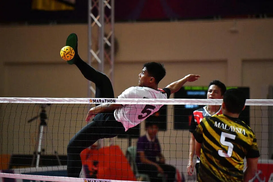 RAIH PENGALAMAN: Pemain Singapura Khairul Fahmi Yazid membuat serangan libas ketika menentang Malaysia dalam acara regu lelaki di Sukan SEA 2023 pada Selasa. - Foto MAJLIS KEBANGSAAN OLIMPIK SINGAPURA